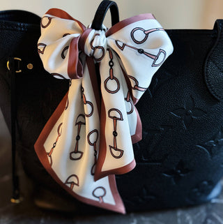 Chain link border scarf with white base, brown ribbon, blue chain print, tied bow on bag