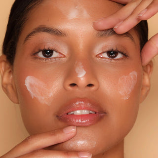 Cleansing balm applied on face with hands near cheeks and forehead