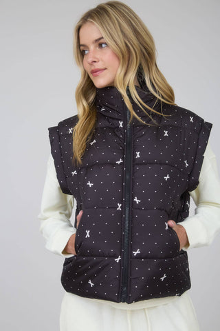 Front view of dark puffer vest with high neck, front zipper, and small light print