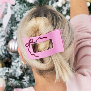 Pink rectangular hair clip with bow outline on blonde bun hair
