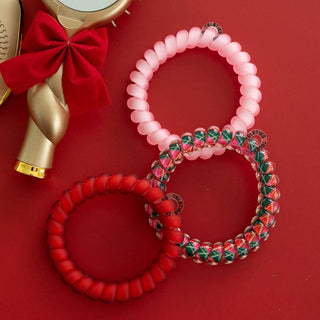 TELETIES large hair ties on red surface: pink coiled tartan ring and solid red ring