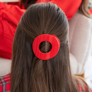 TELETIES red circular hair clip holding dark hair in half-up style