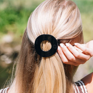 TELETIES jet black flat circle hair clip holding blonde hair back