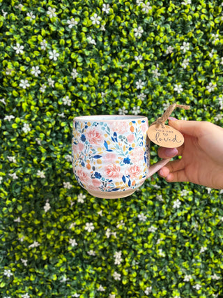 Floral coffee mug with multicolor floral pattern and "You are loved" tag in hand