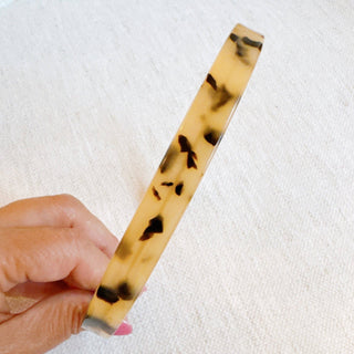 Slim tortoise-pattern headband with curved band and dark speckle design