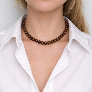 Brown bead necklace worn at the collar with gold-toned chain and clasp