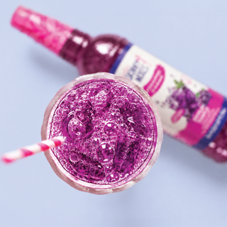 Jordan's Skinny Mixes grape soda syrup drink: close-up of a glass with purple sparkling grape drink and a syrup bottle behind