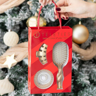 TELETIES Holiday Brush Gift Set in a red striped gift box held in hand