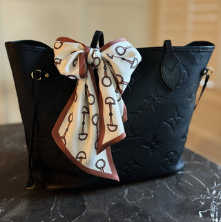 Chain link border scarf tied in bow on black bag, white with blue and brown chain print