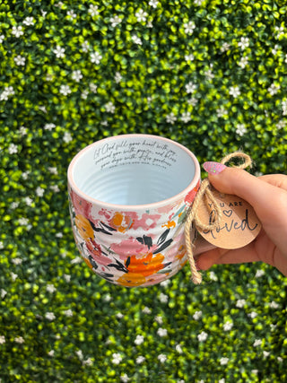 Hand holding floral mug with “You are loved” charm tag, view of interior rim