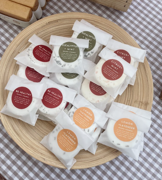 Individually packaged shower steamers in white pouches with citrus and eucalyptus labels.