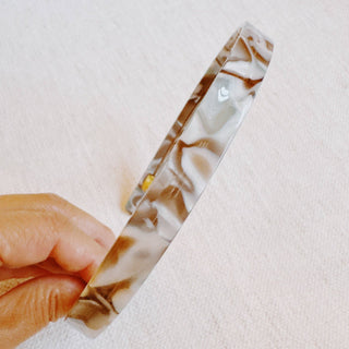 Tortoise-pattern slim headband with clear resin and dark marbling, laid flat