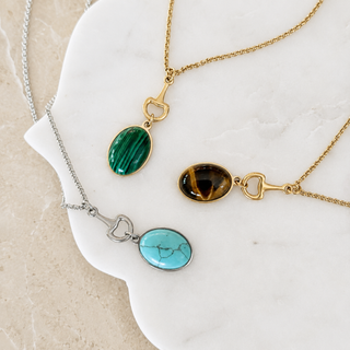 Stone pendant necklace display with gold and silver chains and oval natural stones
