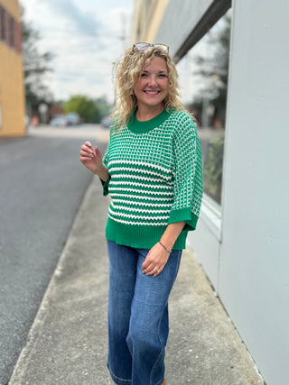 Green knit sweater with white striped pattern, draped sleeves and crew neckline