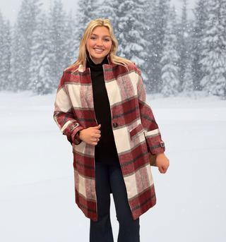 Woman wearing a plaid coat in a snowy forest