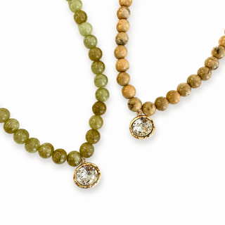 Green and tan beaded necklace with round crystal pendant in gold-tone setting