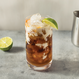 Jordan's Skinny Mixes iced sweet cream dirty soda drink in a clear glass with lime wedge and ice