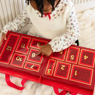 TELETIES red advent calendar with numbered doors 1–12 held by a person in a white sweater