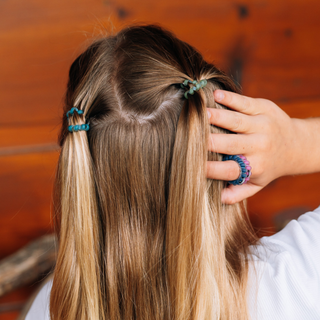 Teleties Sweater Swatches tiny spiral hair ties in teal holding a half-up style in blonde hair