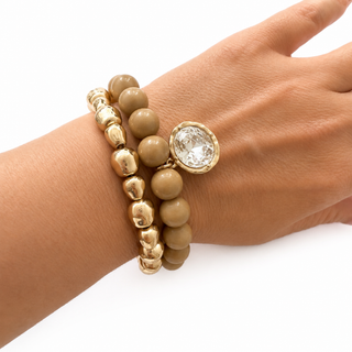 Tan marbled bead stretch bracelet with gold beads and round crystal charm on wrist