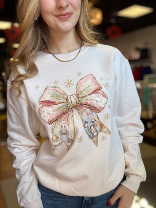 Model wearing the sand Christmas Bow Nativity crewneck sweatshirt with jeans