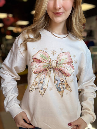 Model in the sand Nativity crewneck sweatshirt with hands at her waist, front view