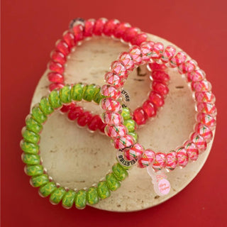 TELETIES set of coiled hair ties in red, pink plaid, and green on round backing