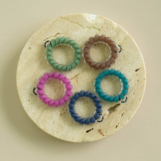 Teleties Sweater Swatches five tiny spiral hair ties in green, brown, pink, teal and navy on a dish