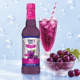 Jordan's Skinny Mixes grape soda syrup bottle with purple soda glass and grapes in a bowl