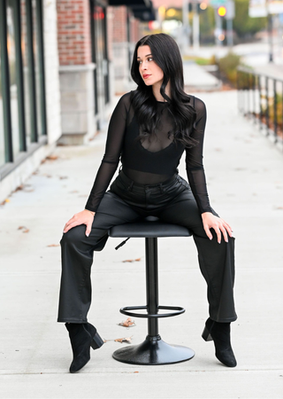 Elietian Seamless Sheer Mesh Top in Black with black pants, seated on a stool