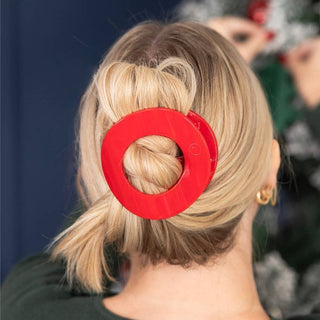 Red flat circular hair clip on blonde hair, visible center cutout