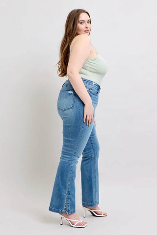 Angled side view of plus-size model in Judy Blue Boot Jeans showing high-rise fit and bootcut leg with slit detail.