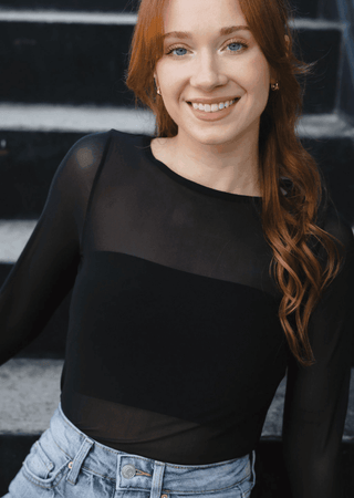 Close-up of black sheer long sleeve top with scoop neckline