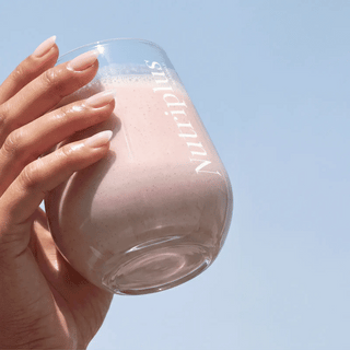 Hand holding clear bottle filled with pink strawberry shake