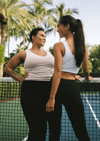 White V-neck sports bra with wide straps, two women wearing
