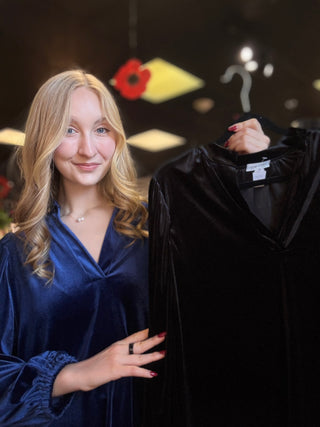 Model wearing the Navy velvet balloon sleeve V-neck dress and holding the Black color on a hanger