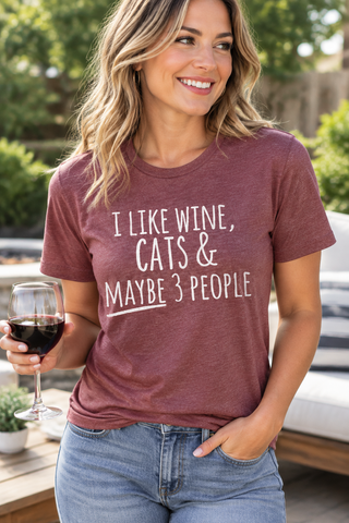 Woman smiling while wearing the I Like Wine, Cats & Maybe 3 People Tee